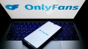 The OnlyFans logo is being displayed on a smartphone screen and on a computer screen