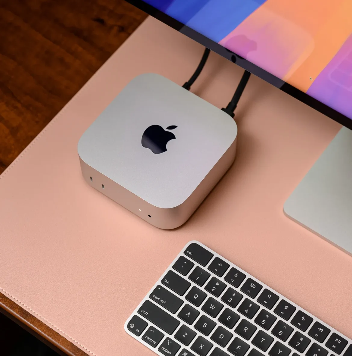 A hands-on photo of Apple’s 2024 Mac Mini on a desk beside a keyboard and Studio Display.