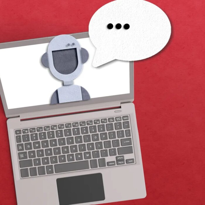 AI agent concept with robot inside a laptop with a voice bubble on red background.