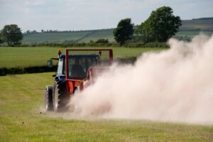 Farmer spreading chicken manure mixed with lime on newly harvested meadow