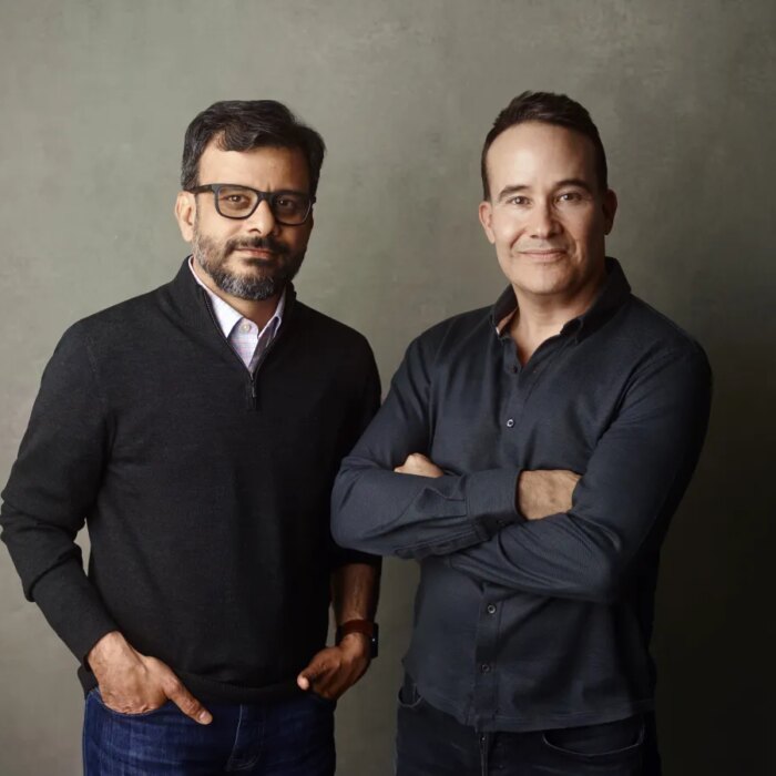 a picture showing the co-founders of Kana, Tom Chavez and Vivek Vaidya, leaning against a grey background