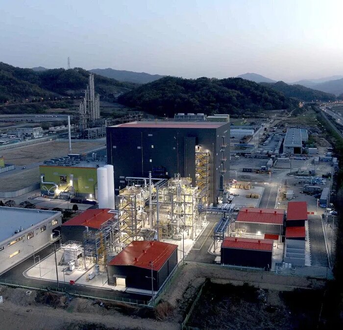 A battery materials factory is lit up at dusk.