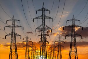 The sun sets behind transmission lines.