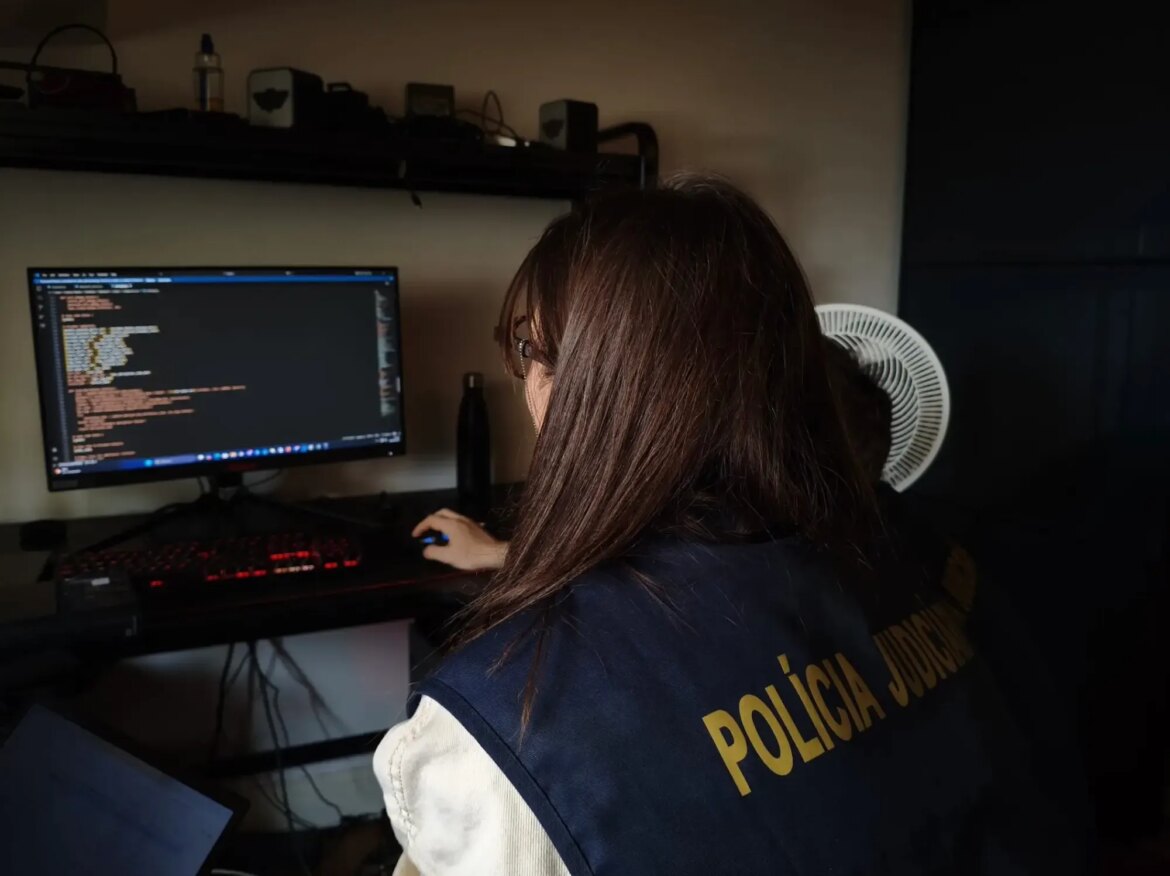 a photo of a European police officer examining a computer at the home of a forum member.