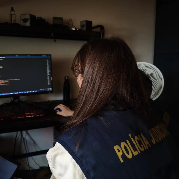 a photo of a European police officer examining a computer at the home of a forum member.