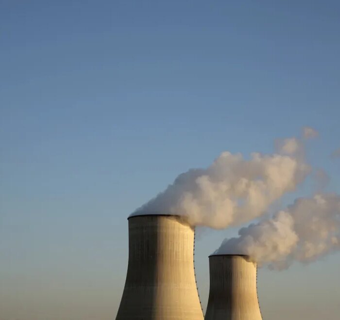 Cooling towers for a nuclear reactor stand against a blue sky.