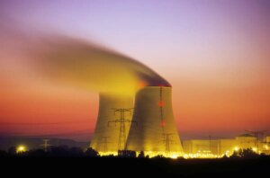 Nuclear power plant cooling towers emit steam at dusk.