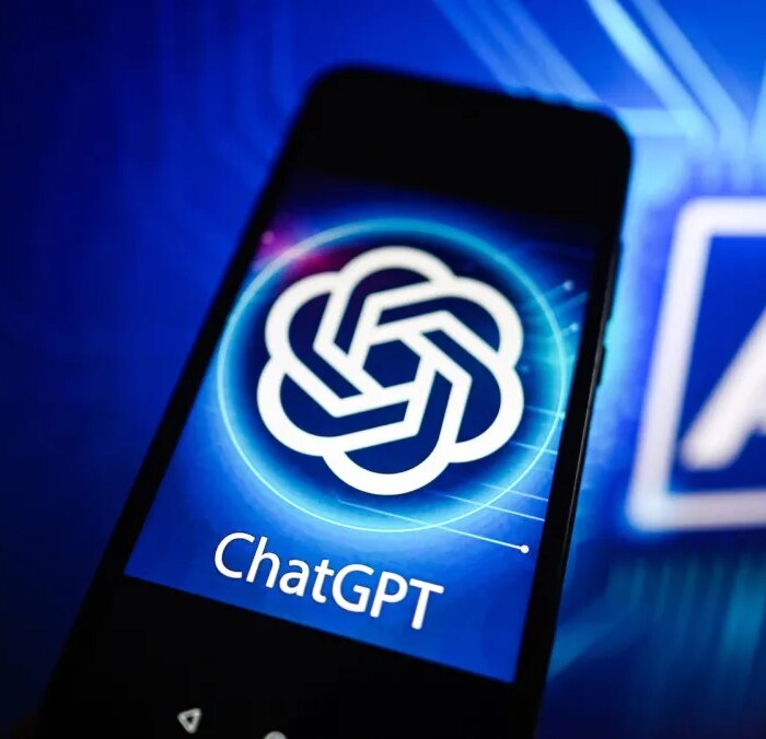 In this photo illustration a Chat GPT logo is seen displayed on a smartphone with Artificial Intelligence (AI) logo in the background.