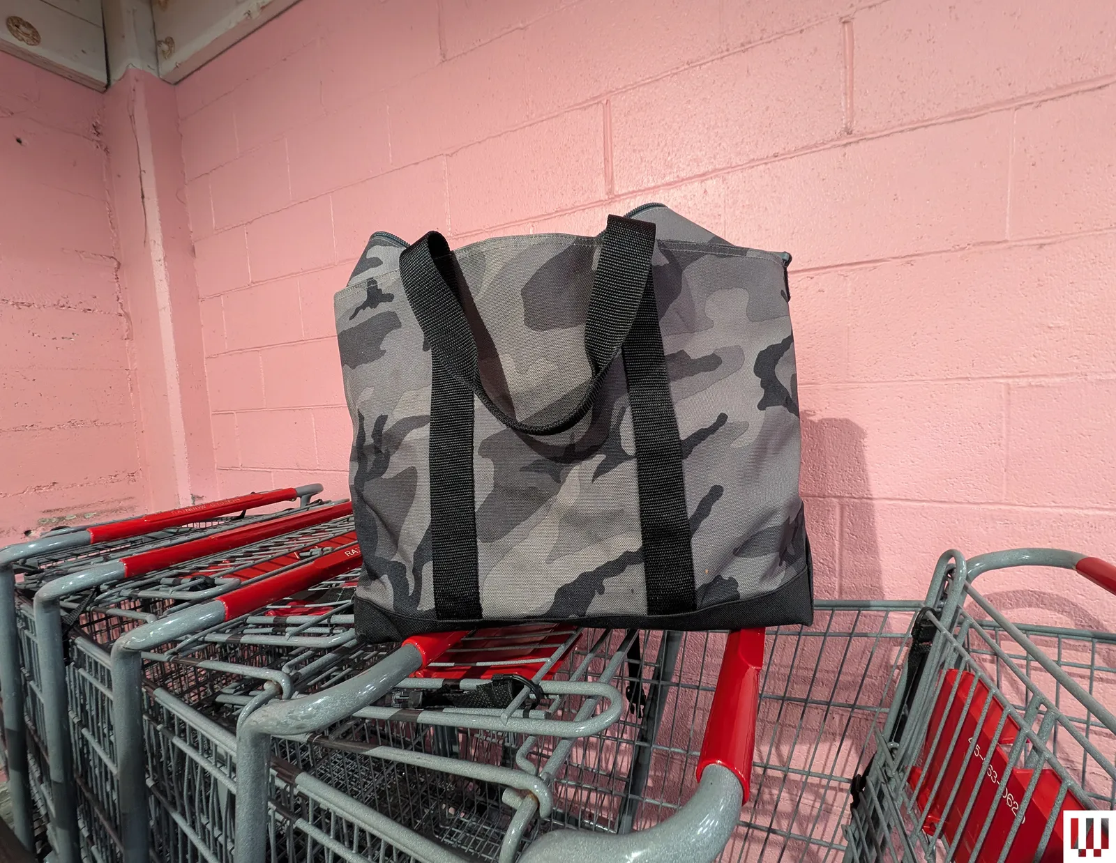 Large tote bag with black and grey camouflage pattern on top of shopping cards