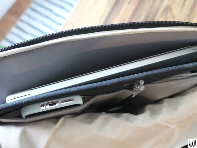 Overhead view of black laptop case partially open to show a laptop, phone, and pen inside