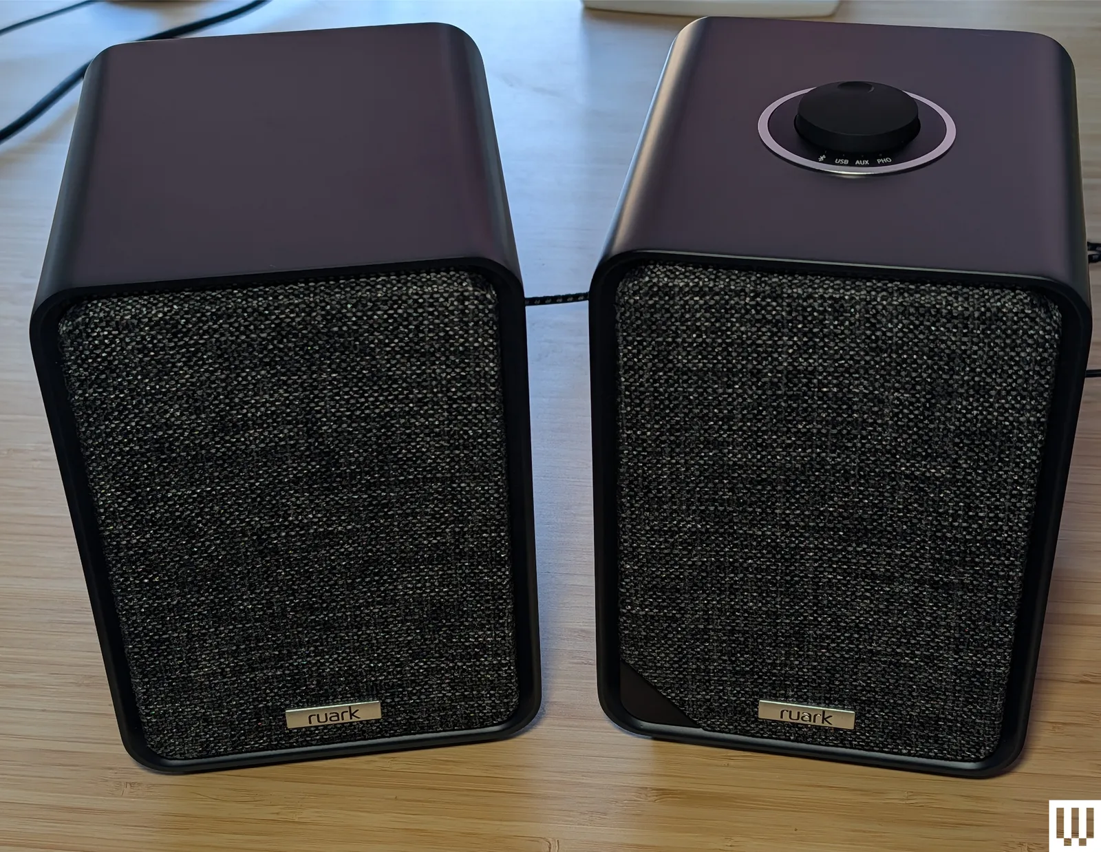 Black rectangular desktop speakers on a hardwood surface