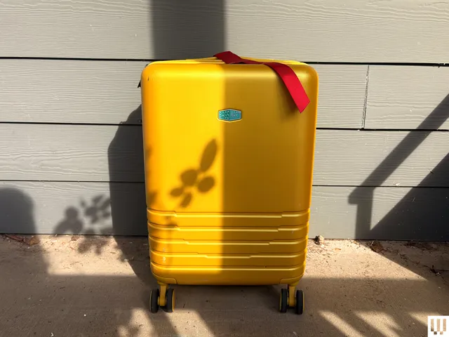 Yellow rolling luggage with red ribbon