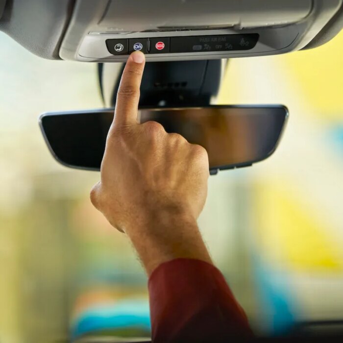 Person pushes the blue OnStar button in a GM vehicle.