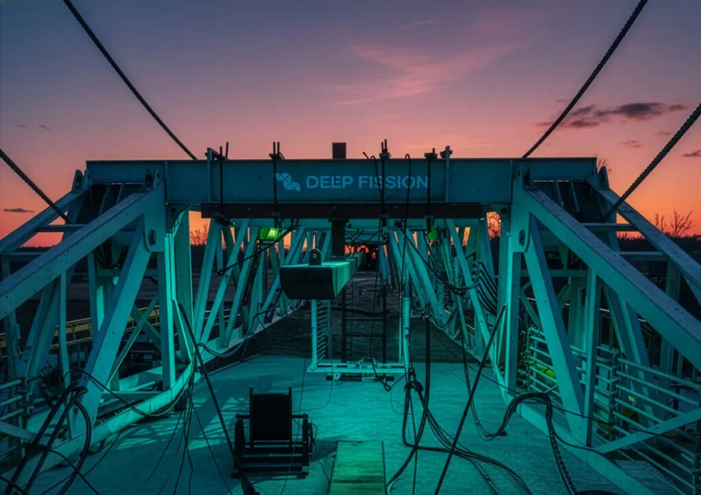 A drilling rig stands in front of a sunset.