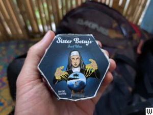 Hand holding a hexagonal shaped container of surfboard wax