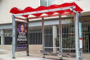 Bus stop shelter with red canopy and ad for Artisan AI reading