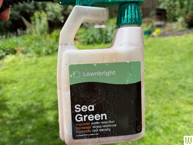 Plastic container attached to a hose with a lush green backyard in the background