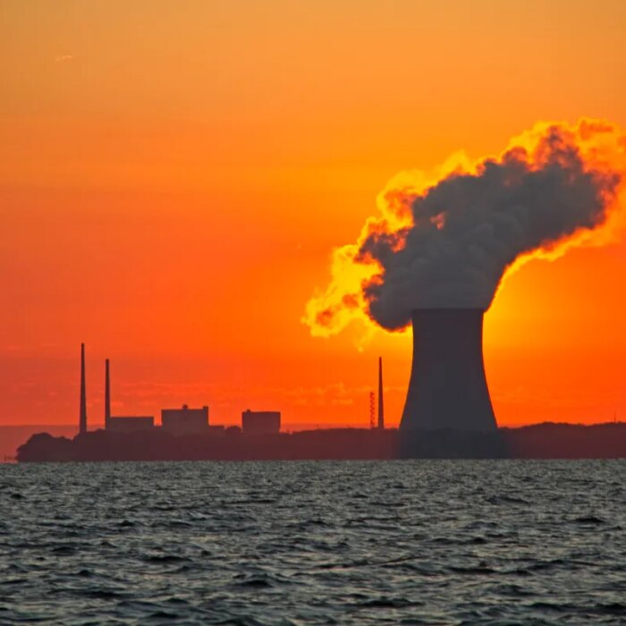 The sun rises behind a nuclear power plant cooling tower.