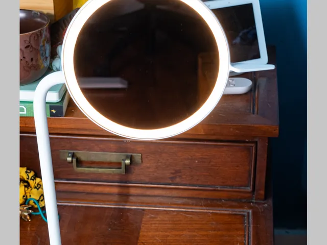 Steelcase Eclipse Light, a circular light with light around the rim attached to a rod leading down to a circular base to charge devices
