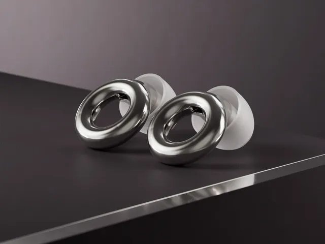 Loop Experience 2, dark grey earplugs with white cushions, sitting on a black surface