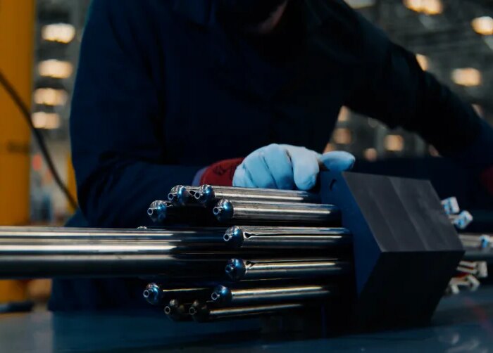 A person handles a nuclear fuel assembly.