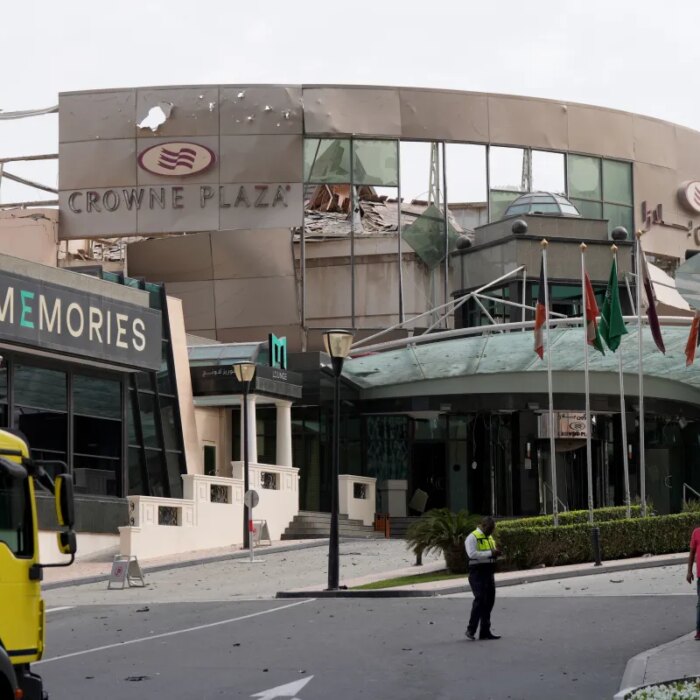 Security and civil defense workers stand outside the damaged Crown Plaza hotel, following an Iranian military strike, in Manama on March 1, 2026.